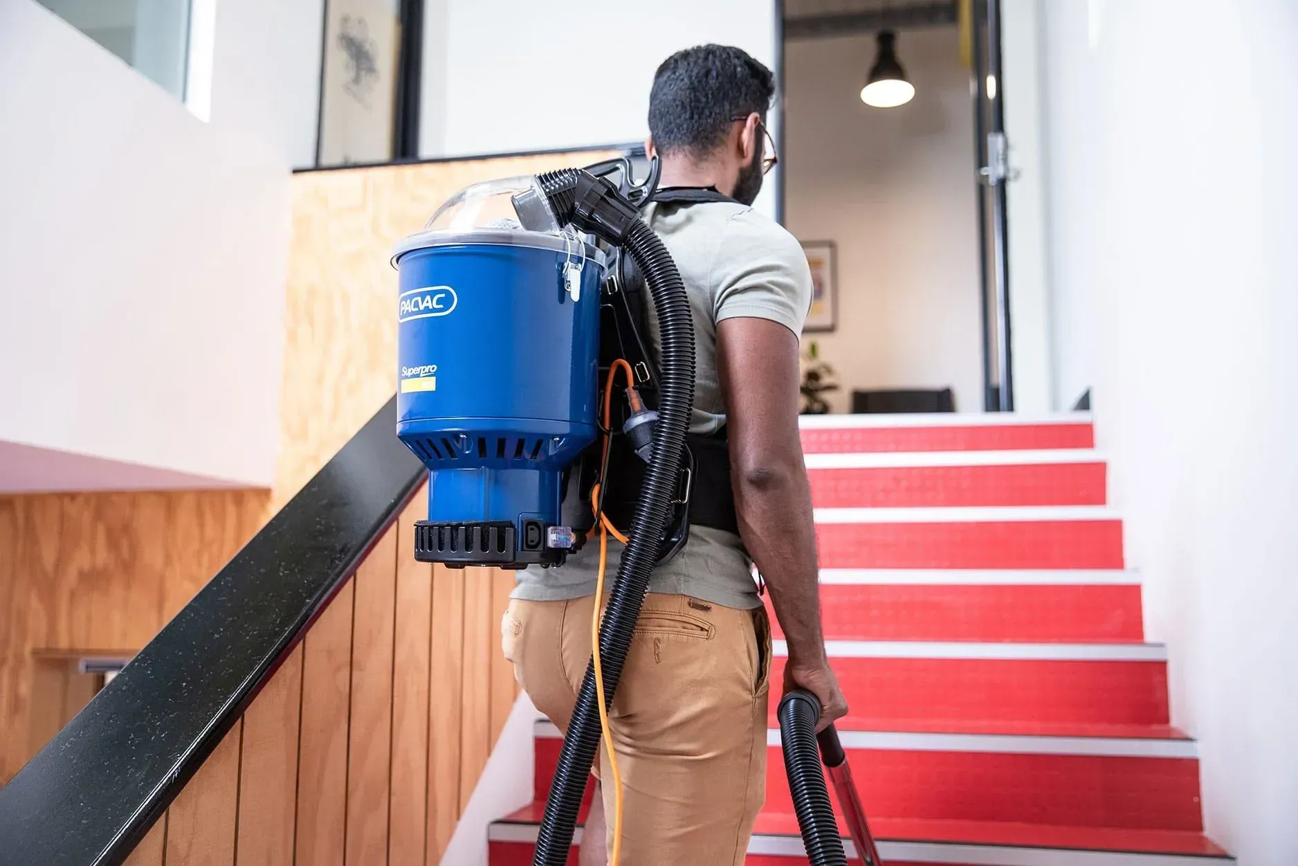 Blue Pacvac Superpro backpack vacuum with black frame and handle.