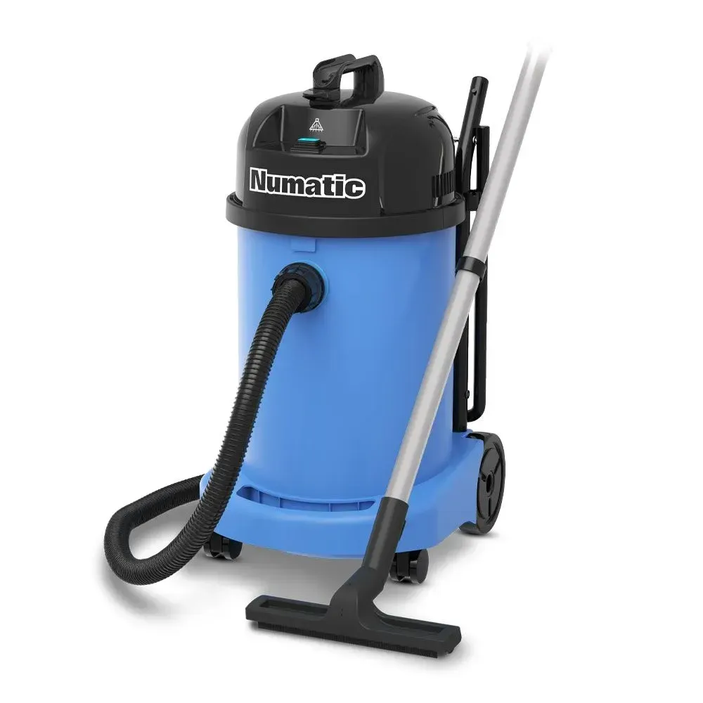 Blue Numatic wet/dry vacuum cleaner with black top and hose, standing on a white surface with attachments.