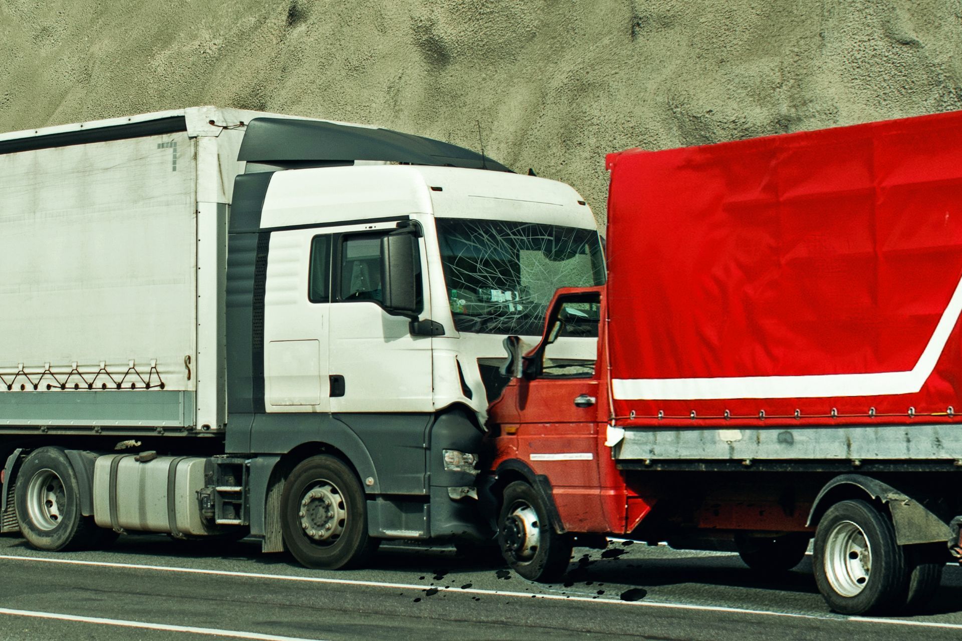 A white truck and a red truck are crashed on a highway.