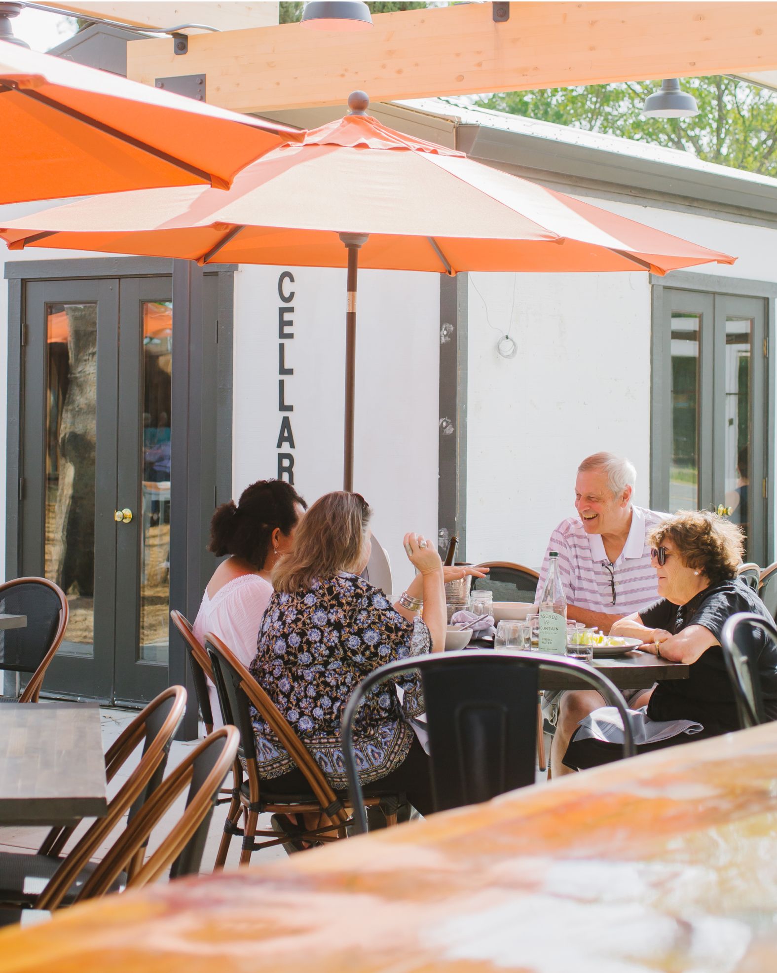 A group of people are sitting at tables under umbrellas in a restaurant.