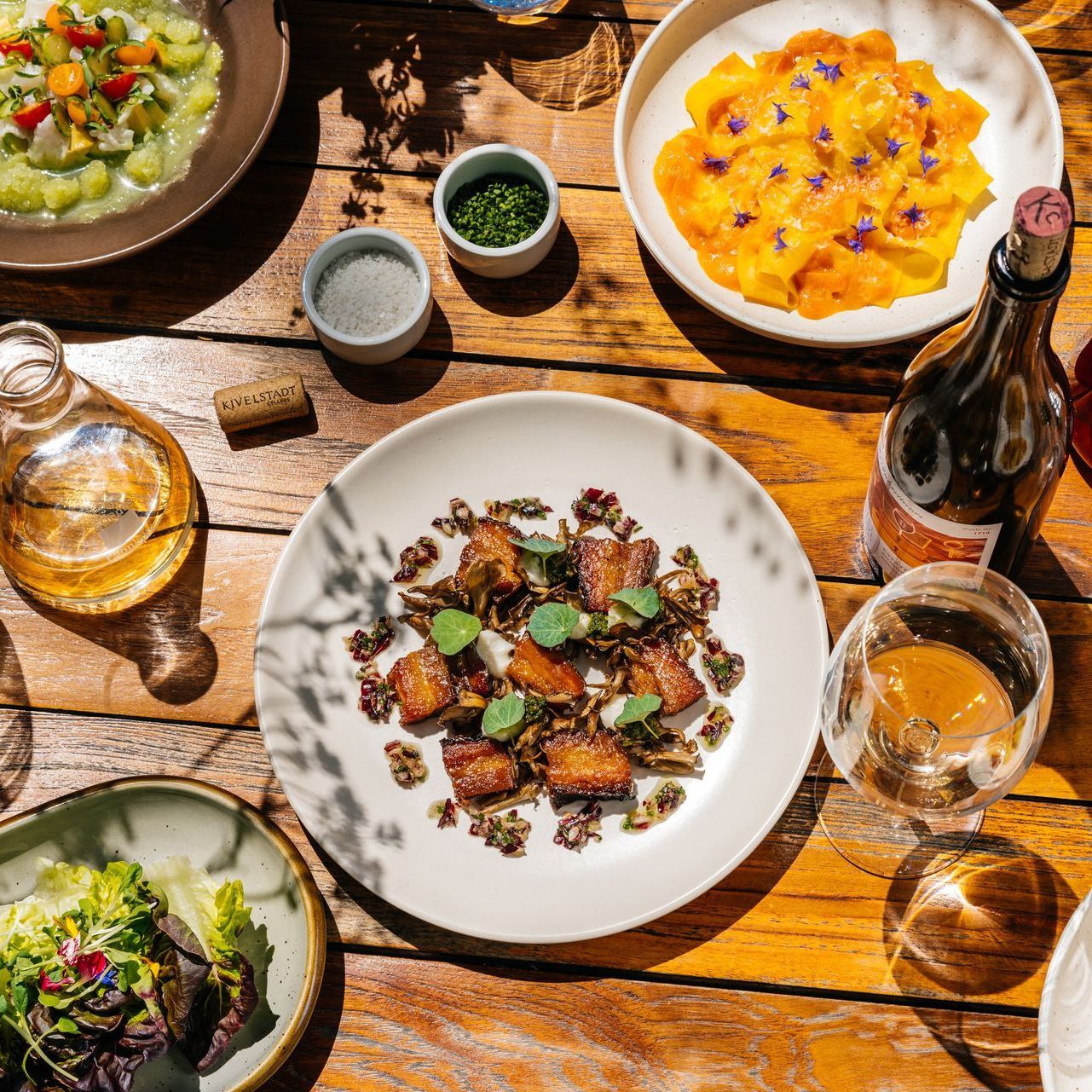 A wooden table topped with plates of food and wine glasses