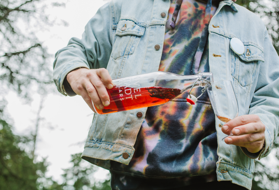 A person is pouring a drink from a bottle into a glass.
