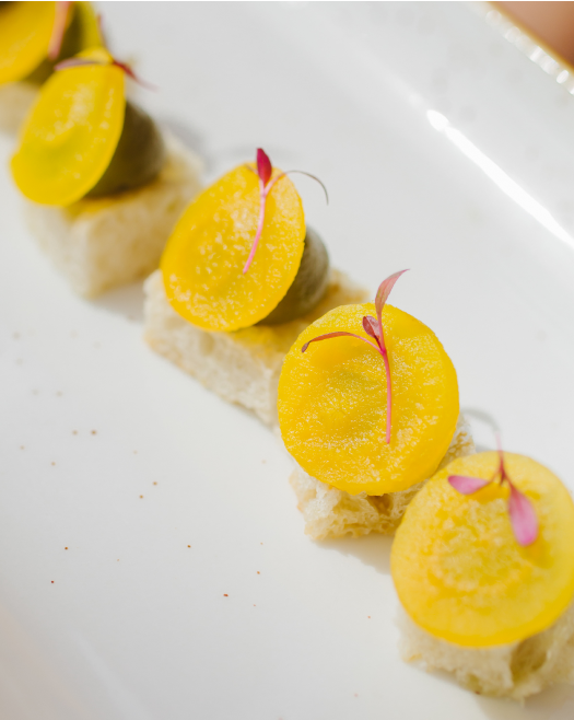 A close up of a white plate topped with yellow slices of fruit.