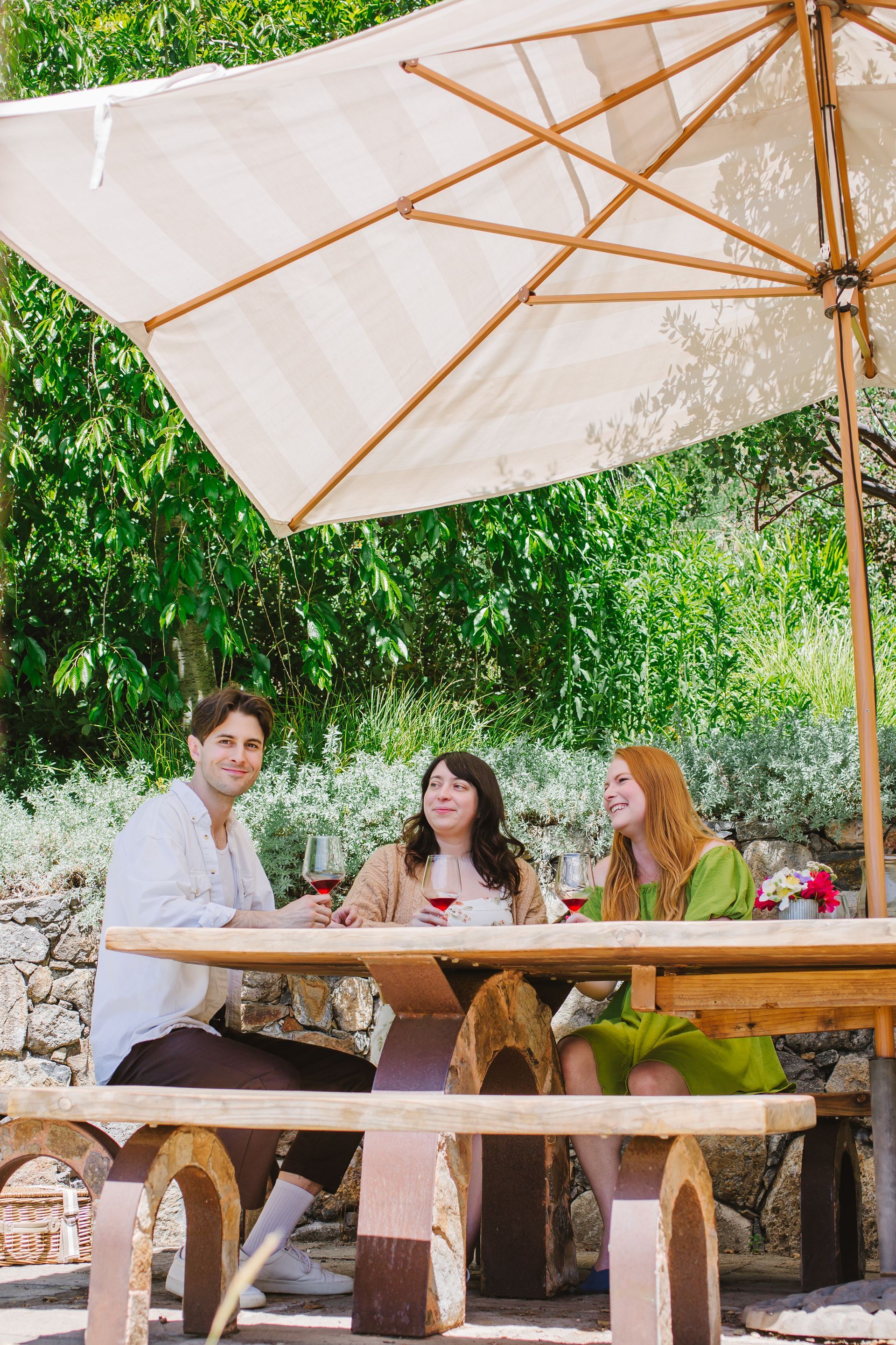 A group of people are sitting at a picnic table under an umbrella.