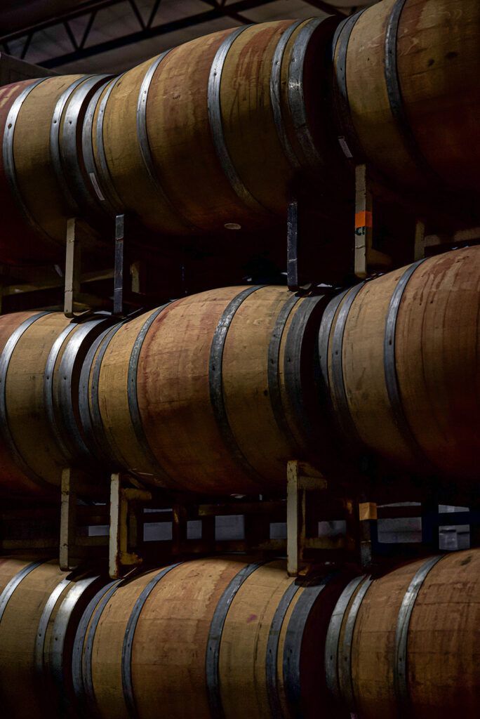 A row of wooden wine barrels stacked on top of each other in a wine cellar.