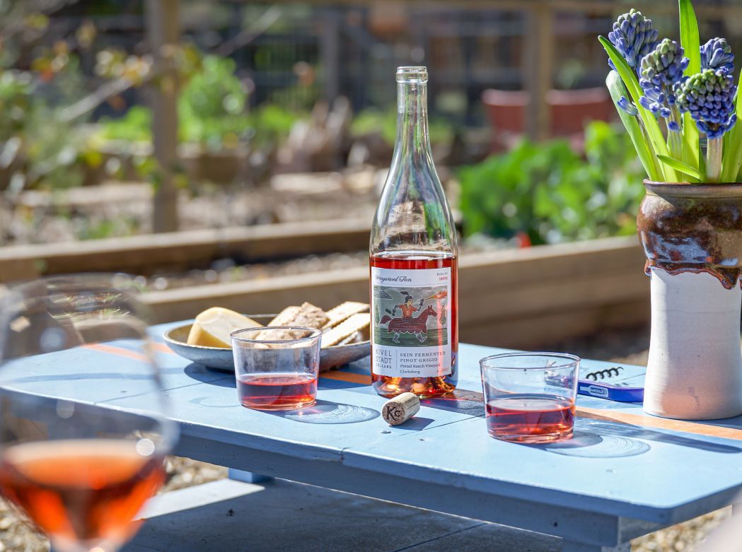 A bottle of wine is sitting on a table next to a vase of flowers.