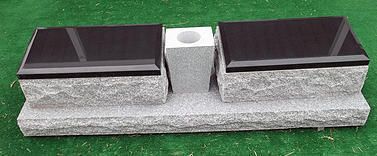 Small metal fixture with two black rectangular plates on a gray base against green background