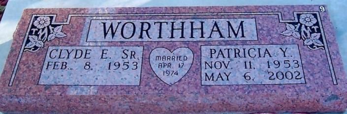 Pink gravestone engraved “WORTHAM” with name and dates on left and right plaques.