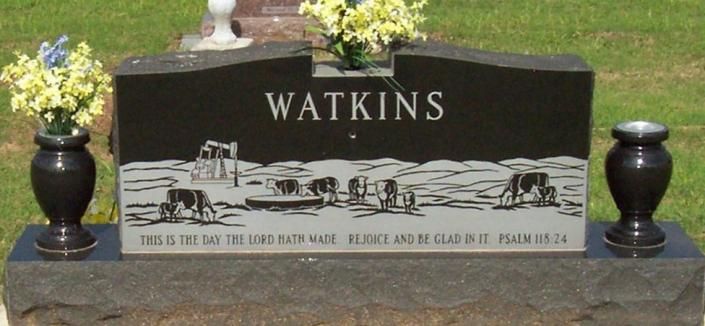Black granite gravestone engraved WATKINS with floral arrangements on either side