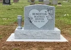 Gray granite gravestone for Bengston Beatrice Griffin with small angel engraving in a grassy cemetery