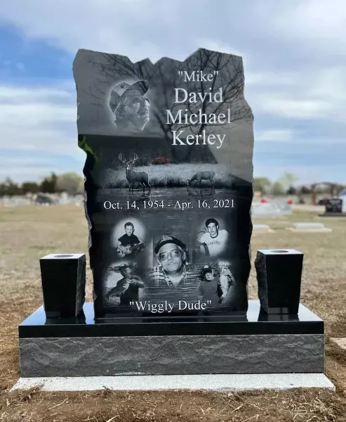 Black memorial headstone with photos, name, dates, and two candle holders in a cemetery