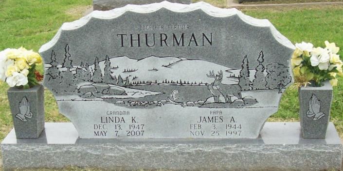 Gray gravestone with tree etching and white flower vases, engraved “TILLMAN” in a cemetery.