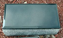 Green metal roof vent cover on a gray shingle roof with wood chips around it