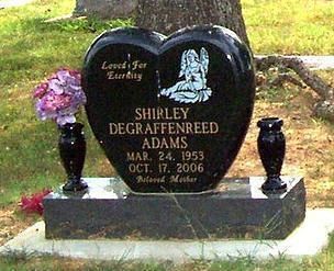 Black heart-shaped gravestone with flowers and vases in a cemetery, memorializing Shirley DeGraffereed Adams.