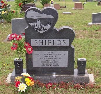 Shields family gravestone with heart-shaped top, black stone, and flowers in a cemetery