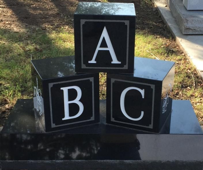 Black and white blocks labeled A, B, and C on a glossy black surface outdoors