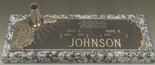 Bronze memorial plaque with engraved name JOHNSON on a granite base, with a small vase holder.