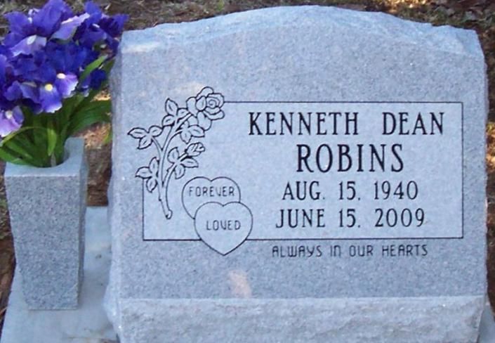 Kenneth Dean Robbins memorial gravestone with floral engraving and purple flowers beside it