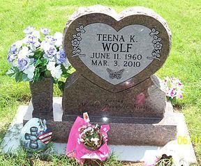 Heart-shaped gravestone with flowers and small tributes at a gravesite.