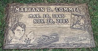 Memorial stone engraved with Maryann D. Lommel, dates, portrait, flowers, fishing scene, and keyboard illustration