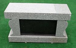 Gray stone rectangular block with a hollow center on green surface