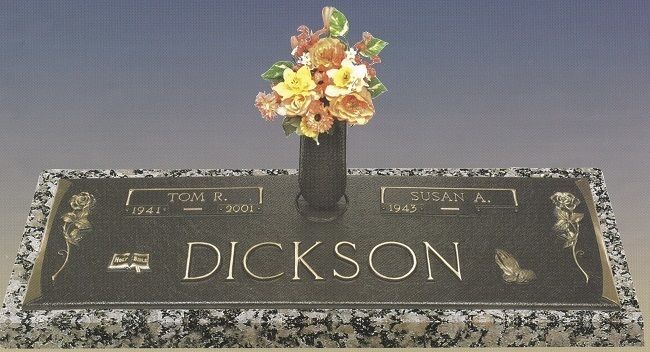 Gravestone for Dickson with flowers in a vase on top, set against a plain background