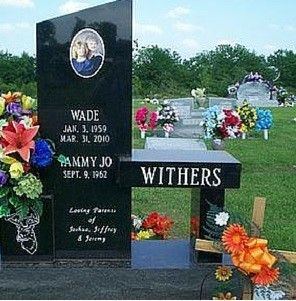 Gravestone memorial with black headstone, flowers, and the name Withers in a cemetery.