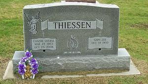 Gray Thiessen gravestone with purple flowers at the base