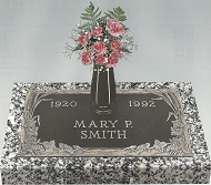 Gravestone engraved “Mary P. Smith” with dates 1920 and 1982, topped by a vase of pink flowers.