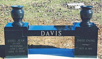 Blue memorial gravestone with “DAVIS” centered, flanked by urns and engraved names on a lawn.