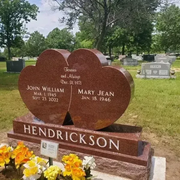 Two-heart gravestone for John William and Mary Jean Hendrickson in a grassy cemetery, with flowers in front
