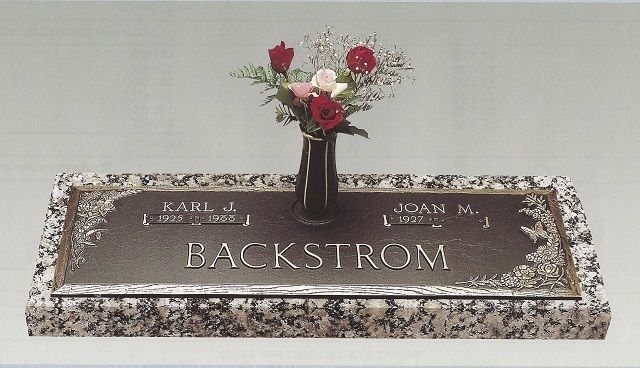 Bronze memorial plaque with flowers in a vase, engraved “BACKSTROM,” on a granite base