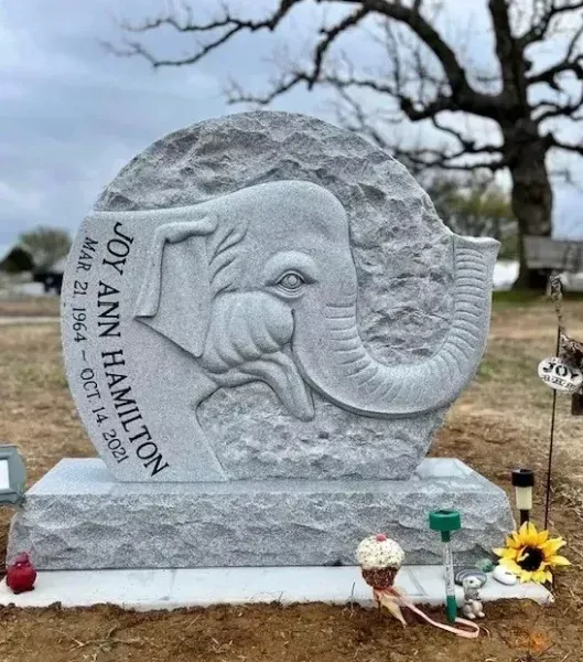Elephant-shaped gravestone for Joy Ann Hamilton in a cemetery, with flowers at the base