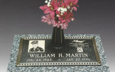 Gravestone plaque for William H. Martin with pink flowers in a vase on a gray surface