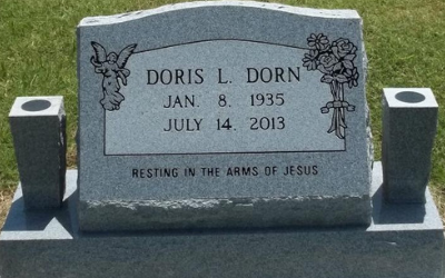 Gray granite gravestone with flowers, reading “Doris L. Dorn,” in a cemetery