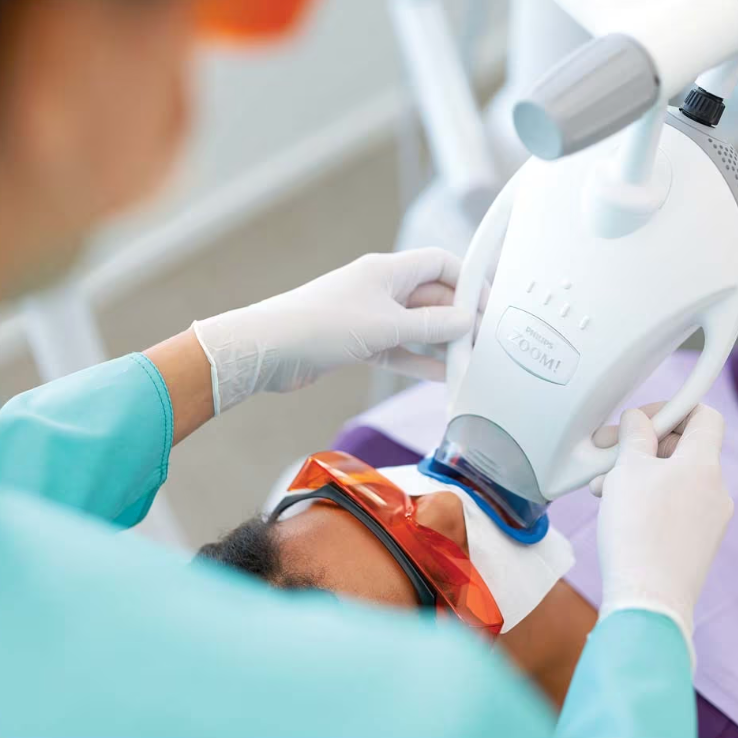 a woman is getting her teeth whitened by a dentist