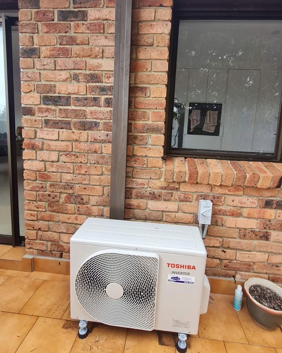 Portable Air Conditioner Outside a Brick House Beside a Window — Alpine Refrigeration & Air Conditioning Pty Ltd in Wollongong, NSW