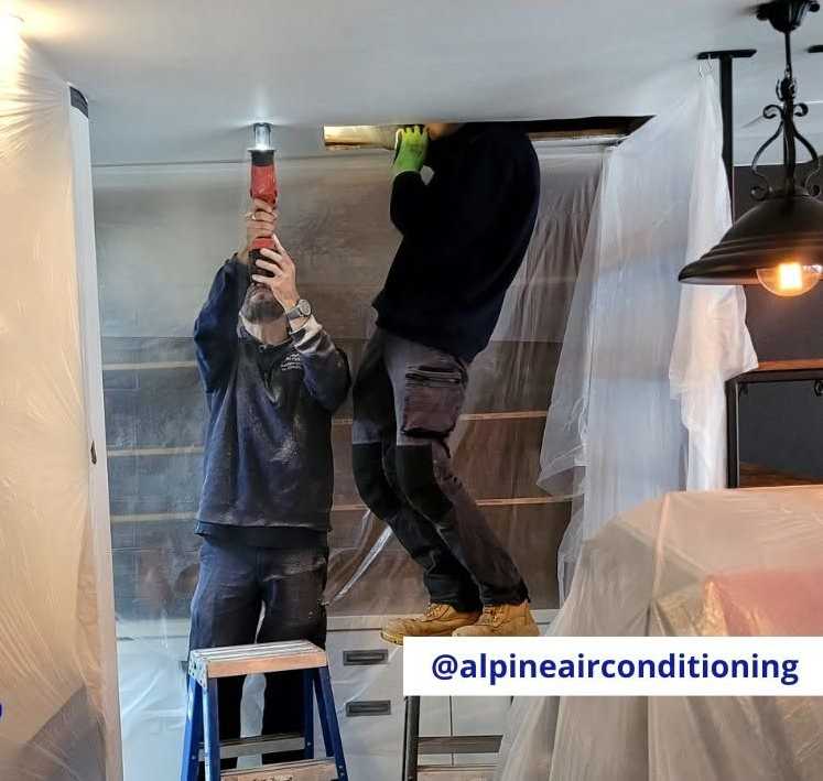 Two Workers Install Ducting in A Room Under Plastic Sheeting — Alpine Refrigeration & Air Conditioning Pty Ltd in Wollongong, NSW
