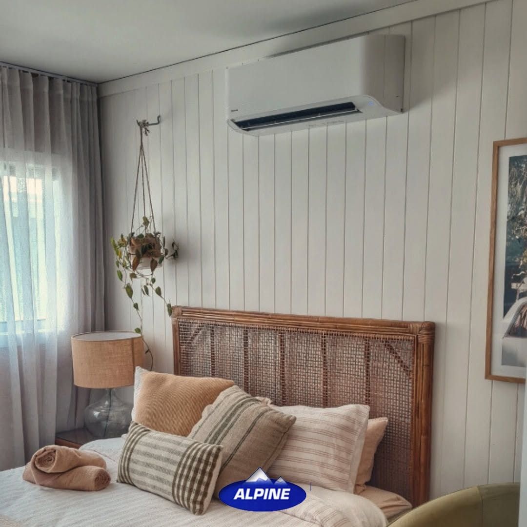Cozy Bedroom with Rattan Headboard, Beige Bedding, Hanging Plant, and Wall-Mounted Air Conditioner — Alpine Refrigeration & Air Conditioning Pty Ltd in Wollongong, NSW