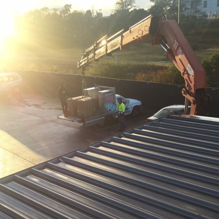 Worker Unloading Cargo from A Truck Beside a Building at Sunset — Alpine Refrigeration & Air Conditioning Pty Ltd in Wollongong, NSW