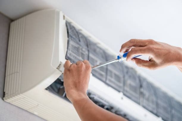 Hands Cleaning An Air Conditioner Filter With A Screwdriver — Alpine Refrigeration & Air Conditioning in Wollongong, NSW