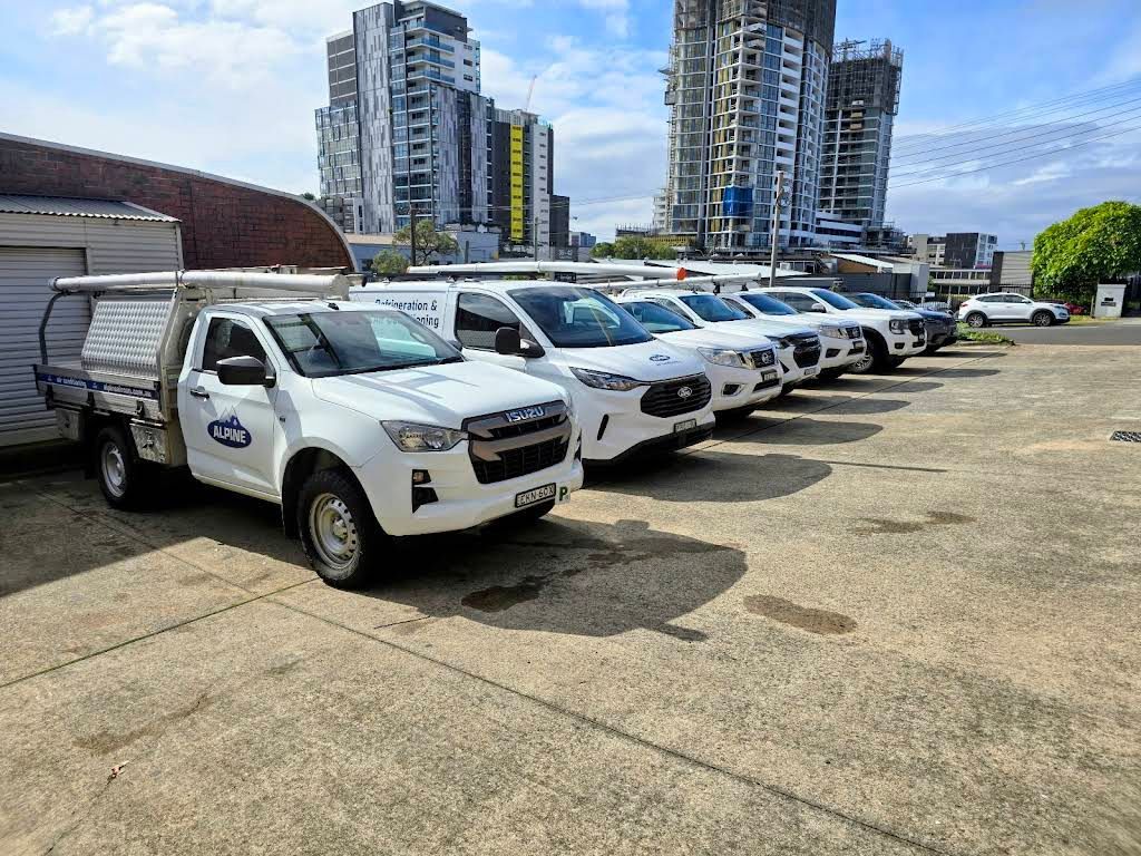 Line of White Pickup Trucks Parked in An Open Lot — Alpine Refrigeration & Air Conditioning Pty Ltd in Wollongong, NSW