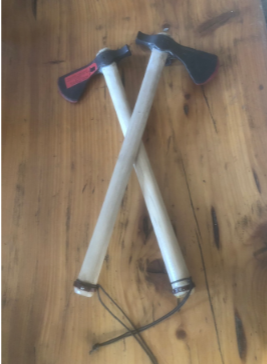 Two crossed axes with white handles and black-and-red heads on a wooden surface