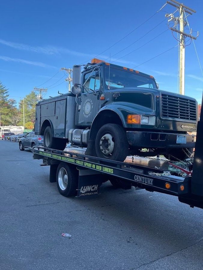 A tow truck is carrying a utility truck on the back of it.