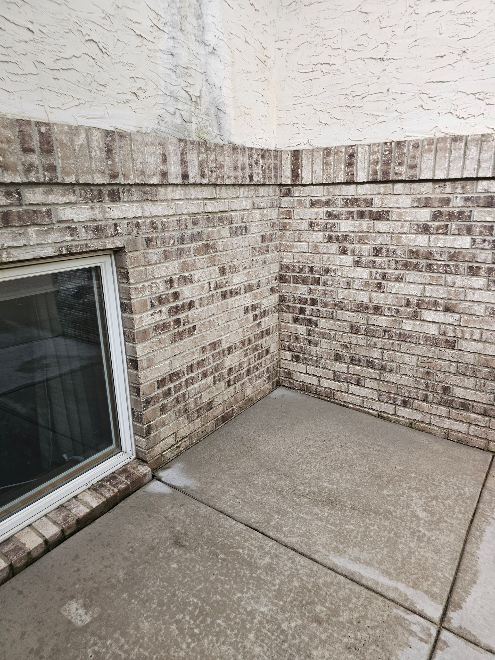 Brick wall and concrete patio with a window.