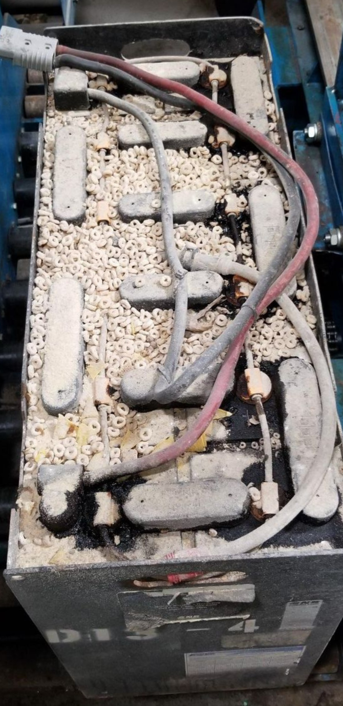 A close up of a dirty battery with wires coming out of it.