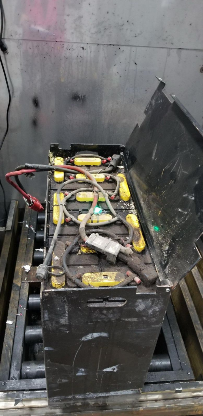 A large battery is sitting on top of a wooden table.
