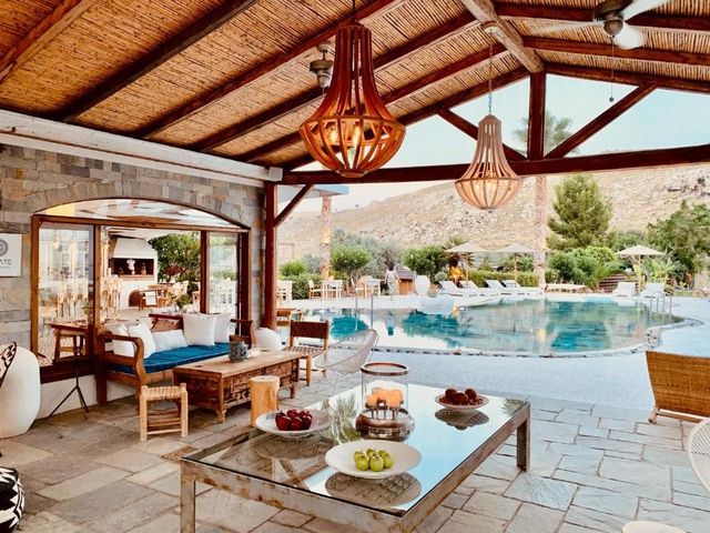 Open-air patio with pool, lounge seating, and a low table with fruit under a thatched roof
