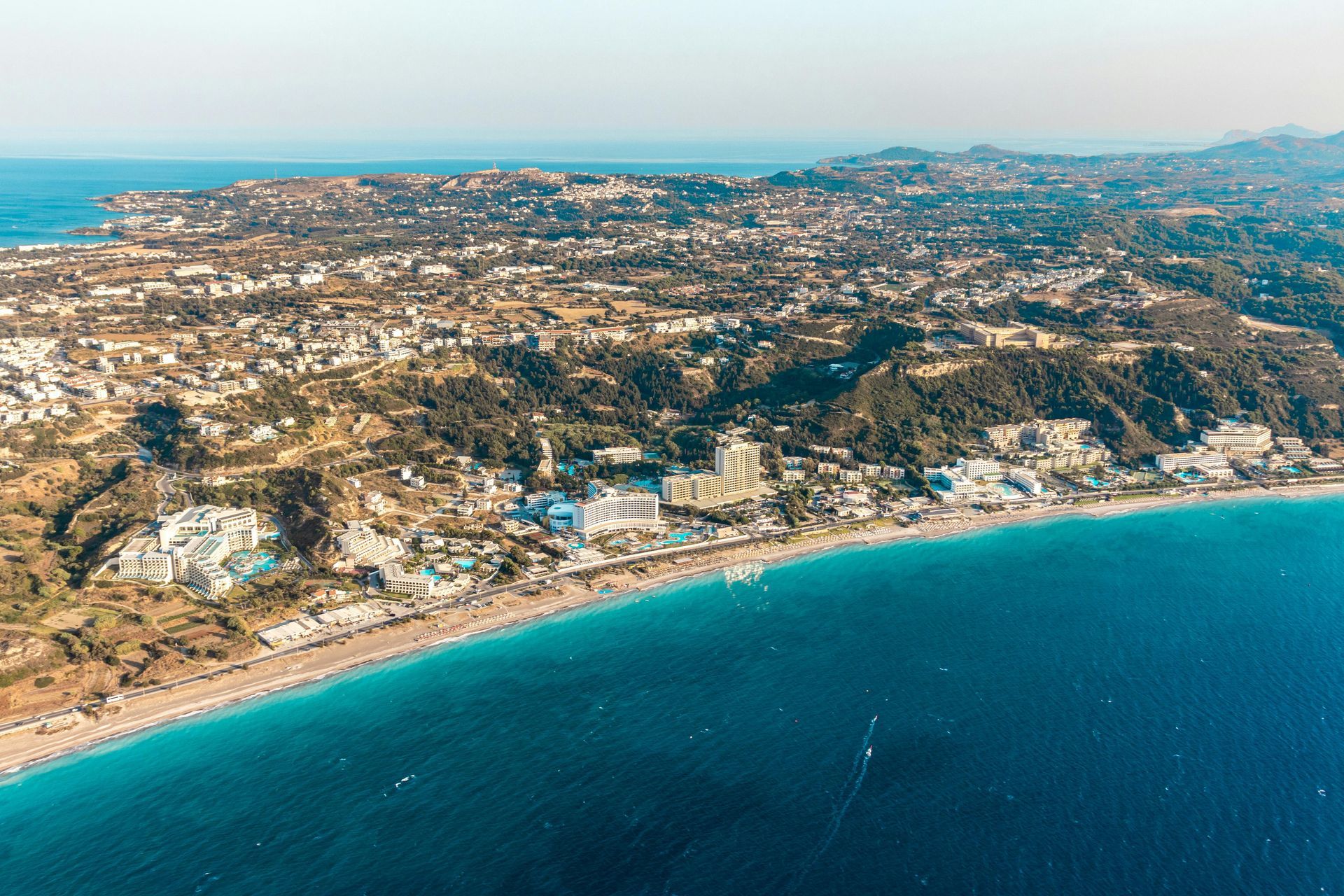 Aerial view of a coastal city with turquoise water and a sandy beach along the shoreline