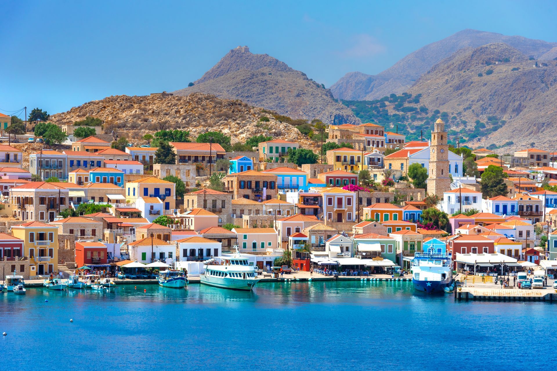 Colorful seaside village with boats in a turquoise harbor and mountains in the background